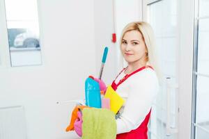 Cleaning lady with a bucket and cleaning products on office background. photo