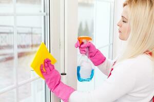 Woman cleaning windows at home with detergents cleaner photo