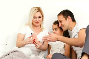 Happy family lies on bed and watching something on laptop. photo