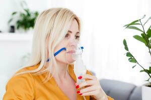 Young woman using nebulizer for asthma and respiratory diseases at home photo