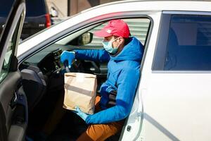 mensajero en protector máscara y médico guantes entrega para llevar alimento. entrega Servicio debajo cuarentena, enfermedad brote, coronavirus covid-19 pandemia condiciones. foto