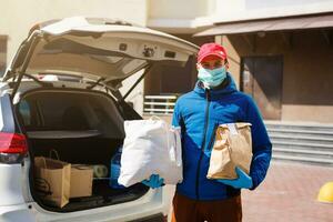 mensajero en protector máscara y médico guantes entrega para llevar alimento. entrega Servicio debajo cuarentena, enfermedad brote, coronavirus covid-19 pandemia condiciones. foto