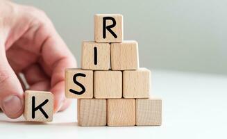 Hand hold wooden cube with risk word. Risk management concept. Selective focus with depth of field photo