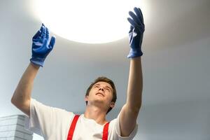 man changing led ceiling lamp in new house photo