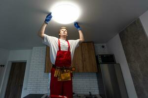 An electrician is installing LED spotlights on the ceiling. photo