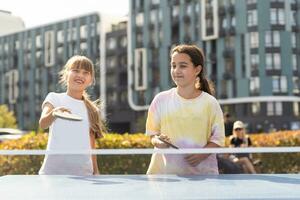 Kid playing table tennis outdoor with family photo