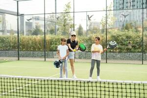 activo joven mujer practicando padel tenis con grupo de jugadores en el tenis Corte al aire libre foto