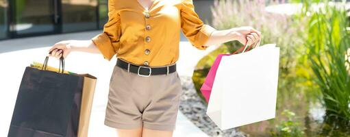 concepto de felicidad, consumo, venta y personas - mujer joven sonriente con bolsas de compras sobre fondo de centro comercial foto