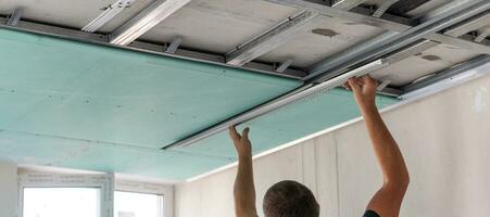 Workers fitting panel into frame of ceiling. photo