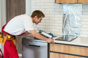 craftsman installs hob in kitchen. Household Appliance Installation Services Concept photo