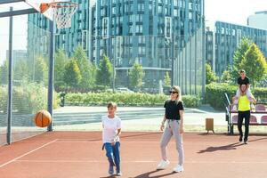 verano vacaciones, deporte y personas concepto contento familia con pelota jugando en baloncesto patio de recreo foto