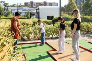 Mother and her little daughter practicing to hit the ball at the course photo