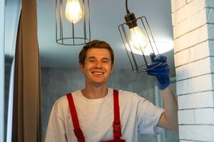 Worker installing lamp on stretch ceiling indoors. photo