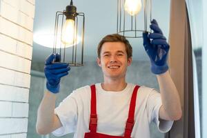 joven hombre instalando techo lámpara en escalera de tijera en cocina foto