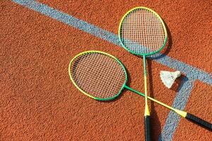 Badminton shuttlecocks and racket, placed in the corner of a synthetic field. photo