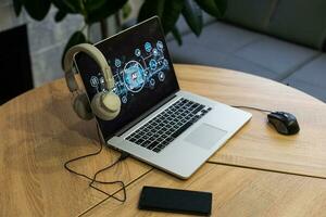 el ordenador portátil con el auriculares en el mesa a hogar foto