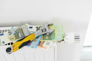 A stack of money on the background of the radiator. Expensive utilities. photo