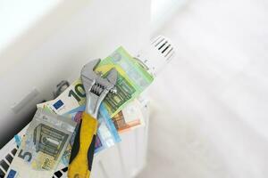 A stack of money on the background of the radiator. Expensive utilities. photo