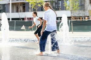 Happy kid playing in a fountain with water photo