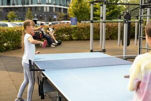 Kid playing table tennis outdoor with family photo