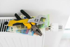 A stack of money on the background of the radiator. Expensive utilities. photo