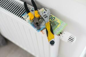 A stack of money on the background of the radiator. Expensive utilities. photo