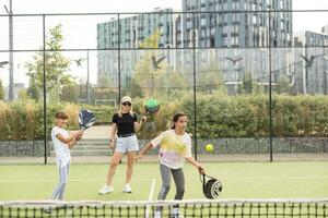 Cheerful coach teaching child to play tennis while both standing on tennis court photo