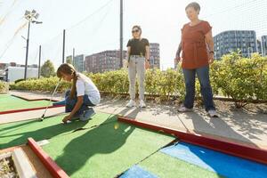 family playing mini golf on a cruise liner. Child having fun with active leisure on vacations. photo