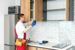 kitchen installation. Worker assembling furniture photo