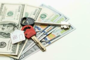 Two keys lie on scattered US dollar bills. The concept of buying real estate, mortgage, home acquisition. photo