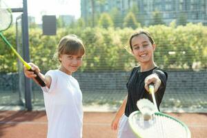 dos muchachas con bádminton raquetas en el fútbol americano campo. foto