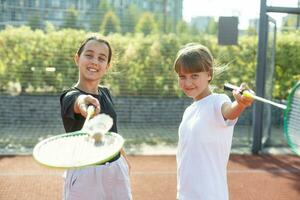 contento deportivo elemental colegio años chica, niño jugando bádminton, participación un raqueta haciendo gracioso caras, retrato, estilo de vida. Deportes, ejercicio y sano al aire libre ocupaciones ocio concepto, uno persona foto