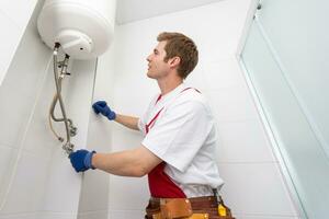 Closeup of plumber using screwdriver while fixing boiler or water heater, working on heating system in apartment photo