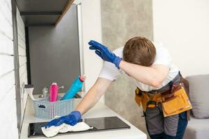 young cheerful man cleaning kitchen dirty household duty spray bottle dust indoors photo