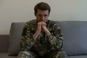 Nervous male military suffering depression, sitting alone at home, PTSD concept. photo