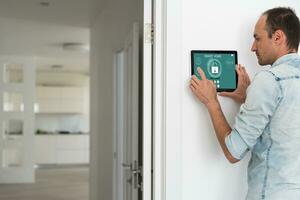 Young electrician installing security alarm on wall photo