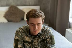 Nervous male military suffering depression, sitting alone at home, PTSD concept. photo