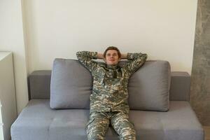 Soldier napping on soft sofa near TV in living room. Military service photo