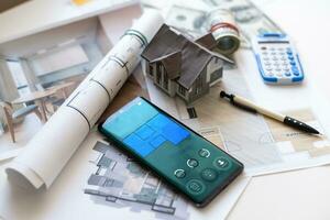 Some Euro banknotes as well as a calculator and a home key on the top of building plans. photo