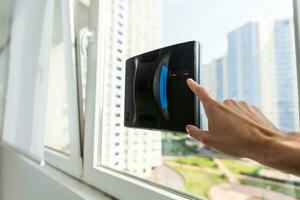 Crop of smart vacuum cleaner washing windows. Home appliance and technology concept photo