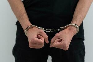 Men's hands closed in chrome handcuffs photo