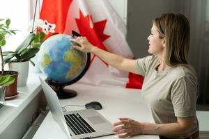 female student sitting with canadian flag and using laptop photo