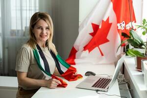 female student sitting with canadian flag and using laptop photo