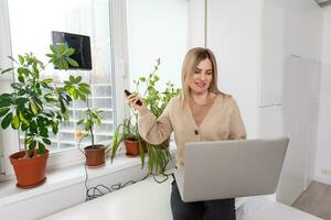 Woman cleaning windows at home with robotic cleaner. photo