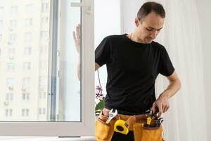 Young repairman fixing window frame in room at daytime photo
