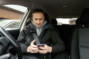 Success in motion. Handsome young man in full suit smiling while driving a car photo