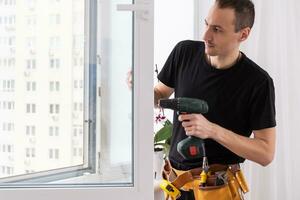 Closeup Of Young African Handyman In Uniform Installing Window photo