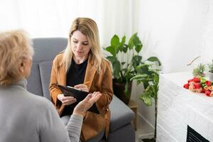 Depressed senior woman talking with female psychologist photo