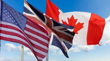 American Flag, Canadian Flag and Flag of Great Britain on blue sky photo