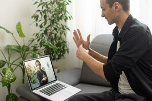 Young man showing gesture in sign language using laptop, make video call photo